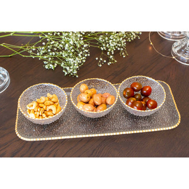 Three small bowls with snacks on a decorative tray on a wooden table.