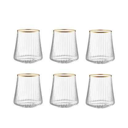 Set of six clear glass tumblers with gold rims on a white background