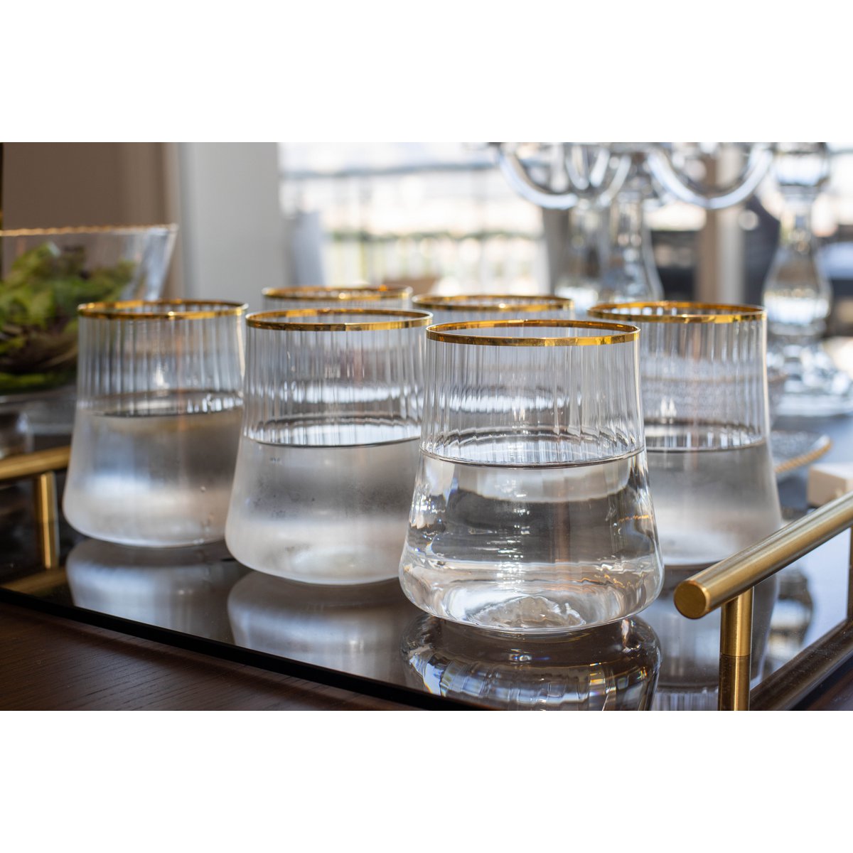 Set of clear glasses with gold rims on a reflective surface