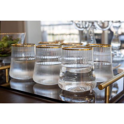 Set of clear glasses with gold rims on a reflective surface