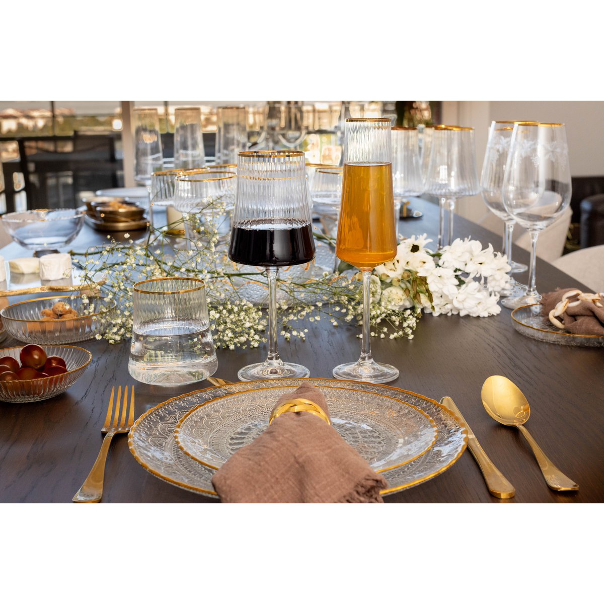 Dining table set with plates, glasses, and cutlery on a wooden surface.