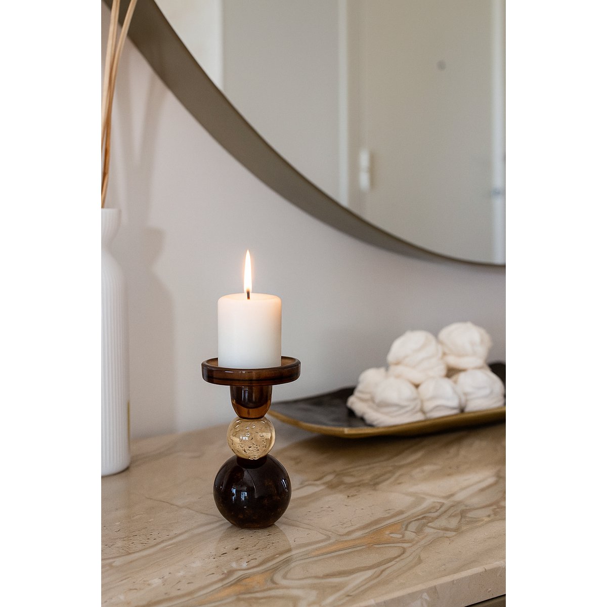 Candle in a decorative holder on a marble surface with a mirror in the background